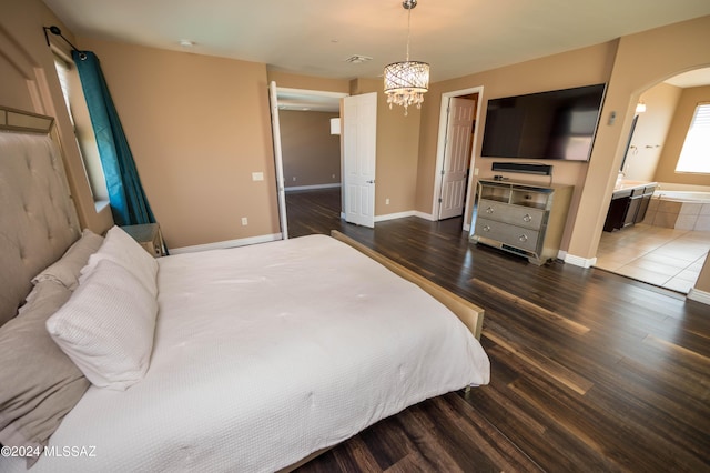 bedroom featuring ensuite bathroom, dark wood-type flooring, and an inviting chandelier