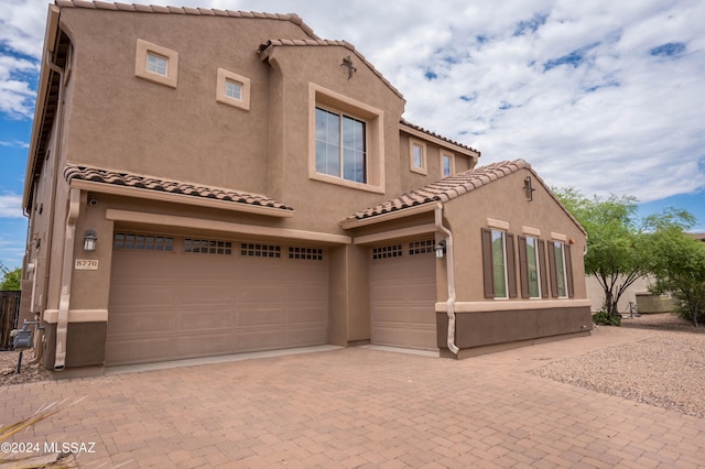 mediterranean / spanish-style house featuring an attached garage, decorative driveway, and stucco siding