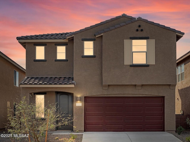 townhome / multi-family property with a tile roof, a garage, and stucco siding