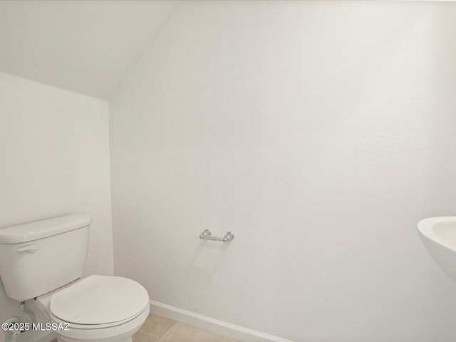 bathroom featuring toilet, tile patterned floors, vaulted ceiling, and baseboards