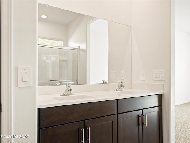 full bathroom featuring a sink, a shower with door, and double vanity