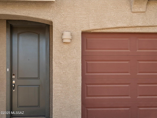 property entrance with a garage and stucco siding