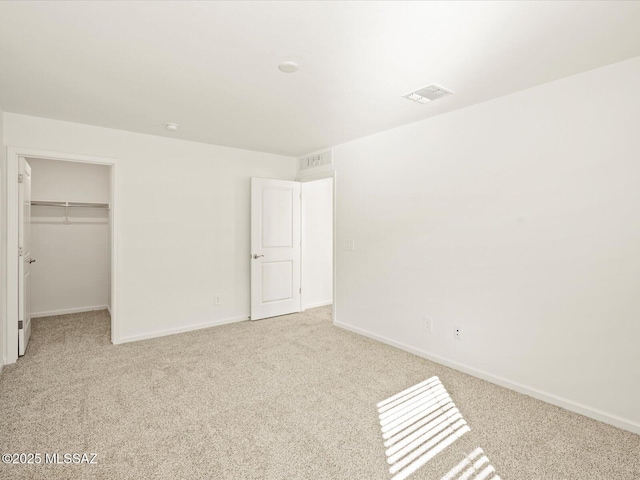 unfurnished bedroom featuring visible vents, baseboards, carpet floors, and a spacious closet
