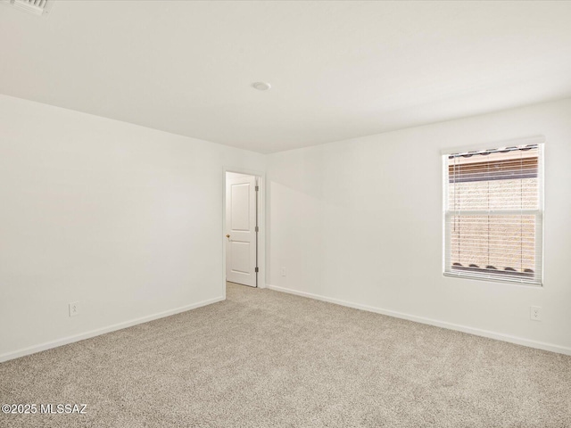 spare room with baseboards and light colored carpet