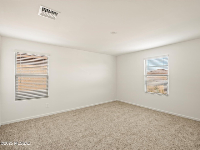unfurnished room with visible vents, carpet, and baseboards