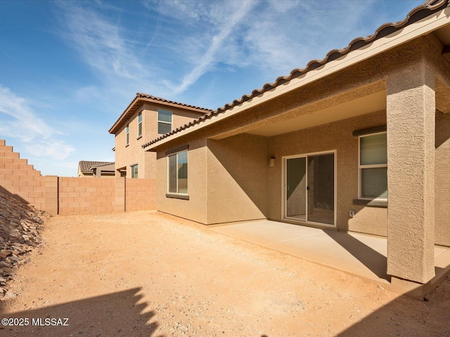 back of house featuring fence, a patio, stucco siding, and a tiled roof