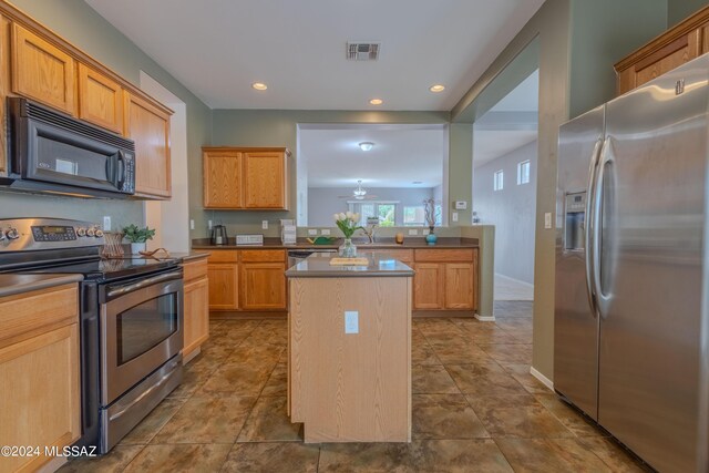 kitchen featuring dark tile patterned floors, stainless steel appliances, a center island, and sink