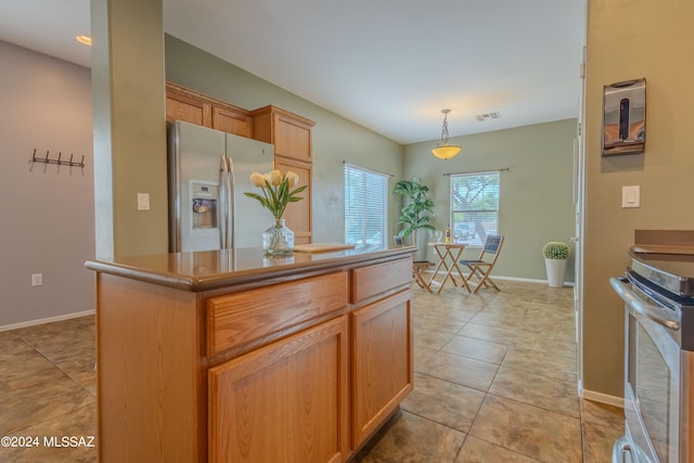 kitchen with stove, pendant lighting, light tile patterned floors, and stainless steel fridge with ice dispenser