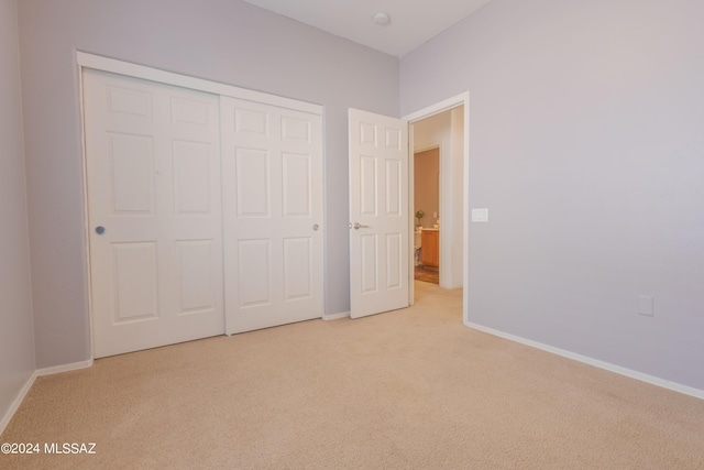 unfurnished bedroom featuring light colored carpet and a closet