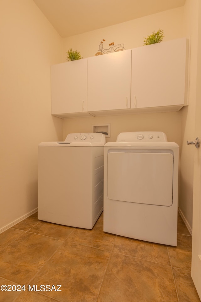 laundry room with light tile patterned flooring, washing machine and clothes dryer, and cabinets