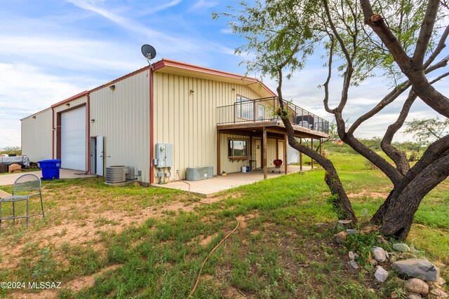 back of house featuring central air condition unit, a lawn, and a patio area