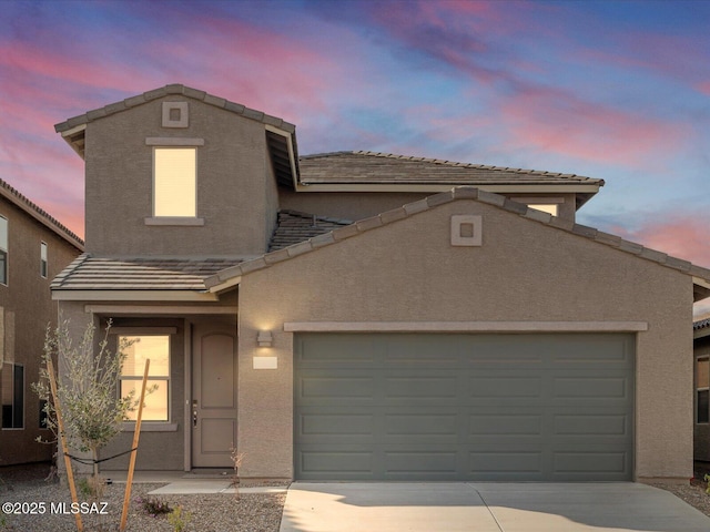 traditional home with stucco siding, a garage, driveway, and a tile roof