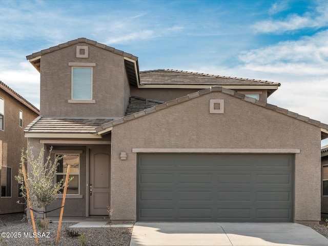 traditional-style home featuring a garage, concrete driveway, a tiled roof, and stucco siding