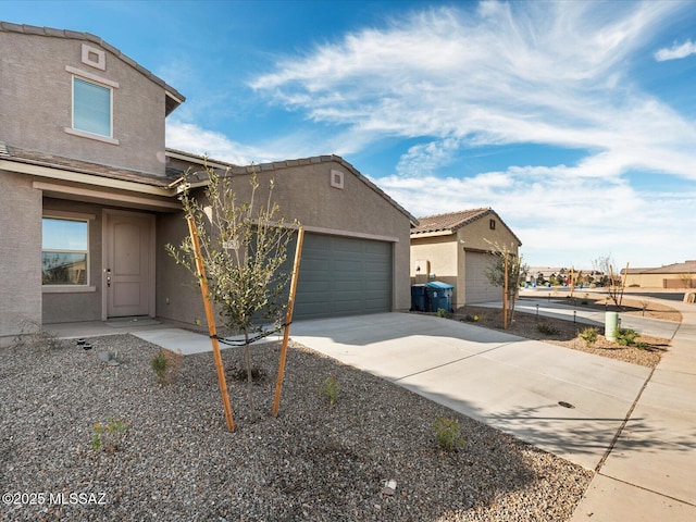 view of front of home featuring driveway, an attached garage, and stucco siding