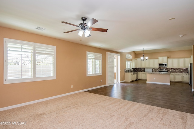 unfurnished living room with ceiling fan with notable chandelier and dark carpet