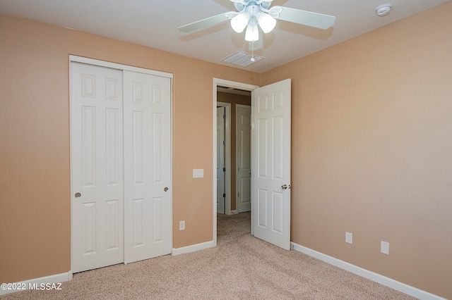 unfurnished bedroom featuring ceiling fan, light colored carpet, and a closet