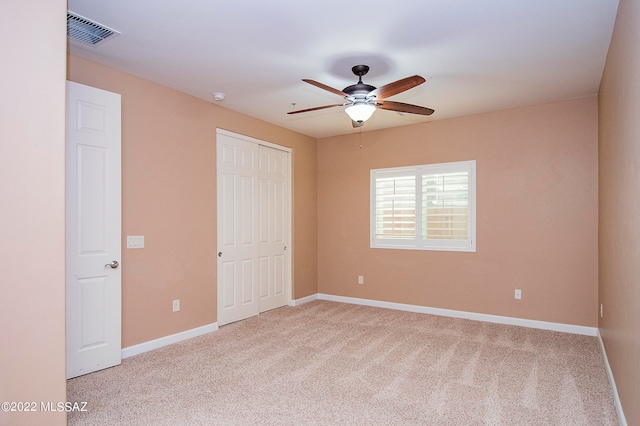 unfurnished bedroom featuring ceiling fan, a closet, and light carpet