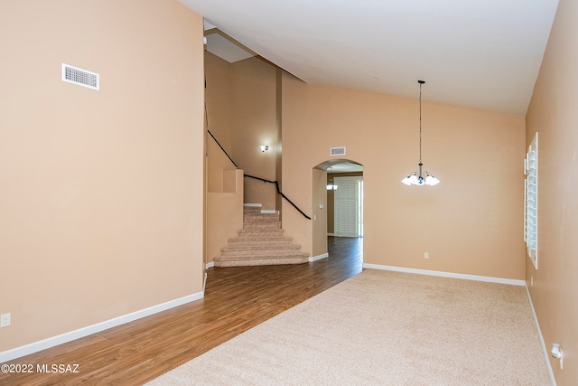 spare room featuring a notable chandelier, high vaulted ceiling, and hardwood / wood-style flooring