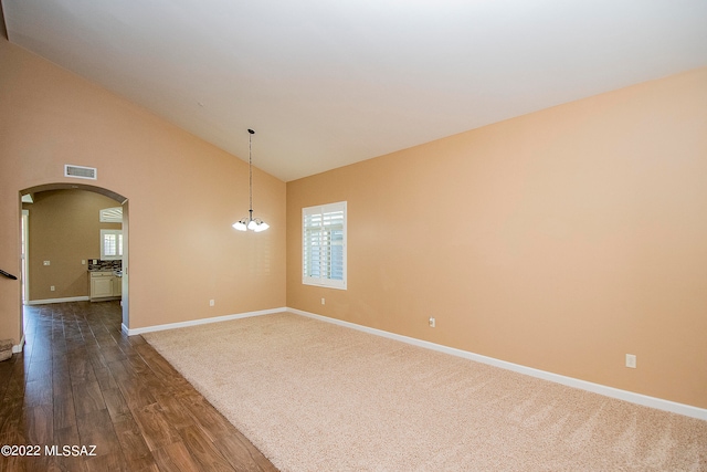 carpeted spare room featuring high vaulted ceiling and a chandelier