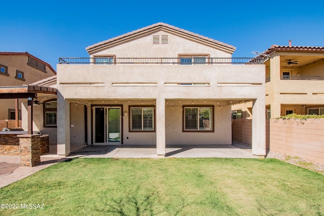 rear view of house featuring ceiling fan, a patio, a lawn, and a balcony