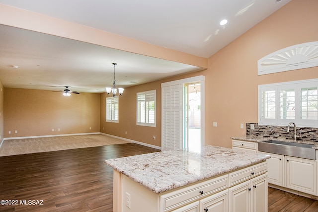 kitchen with a center island, sink, light stone countertops, carpet floors, and tasteful backsplash