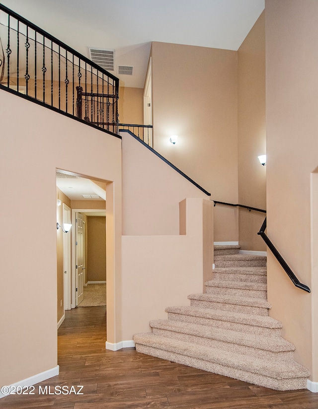 stairway featuring a high ceiling and wood-type flooring