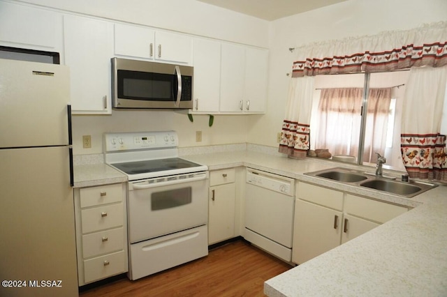 kitchen with white appliances, dark hardwood / wood-style flooring, sink, and white cabinets