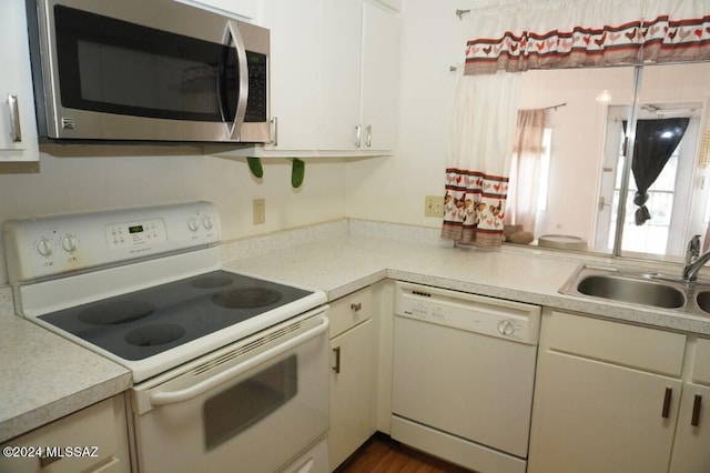 kitchen featuring white appliances, white cabinets, light countertops, and a sink