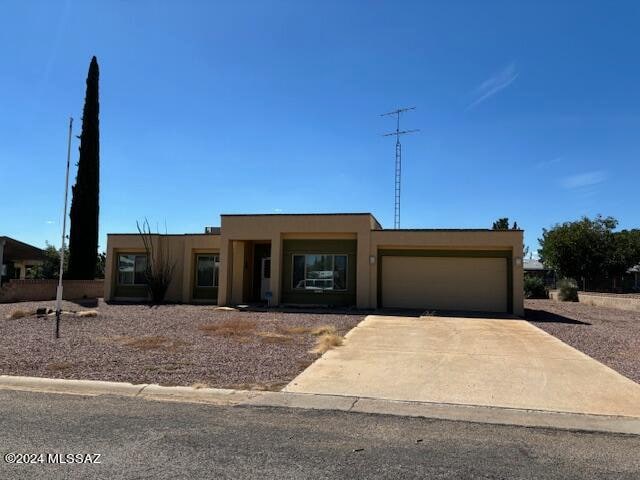 pueblo-style home with stucco siding, an attached garage, and concrete driveway