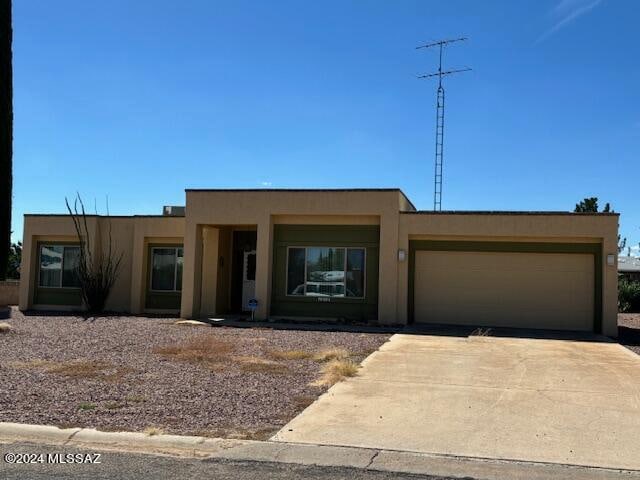 adobe home featuring stucco siding, driveway, and an attached garage