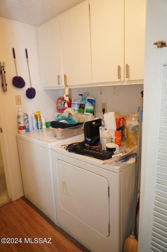 laundry area featuring light wood-style floors, cabinet space, a textured ceiling, and washing machine and clothes dryer