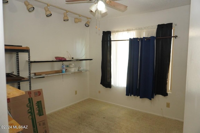 unfurnished room with rail lighting, baseboards, a ceiling fan, and carpet flooring