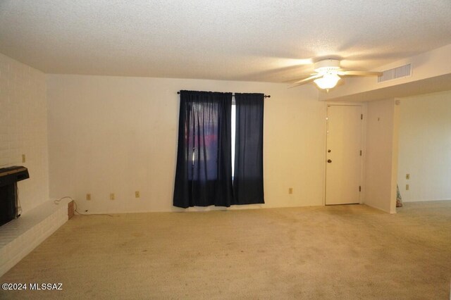 carpeted spare room with visible vents, a textured ceiling, and a ceiling fan