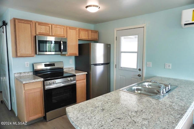 kitchen with appliances with stainless steel finishes, sink, hardwood / wood-style flooring, kitchen peninsula, and a wall unit AC