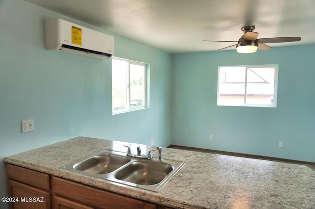kitchen with light countertops, an AC wall unit, baseboards, a sink, and a ceiling fan