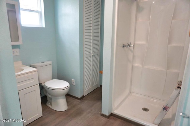 full bathroom with a stall shower, a closet, toilet, vanity, and wood finished floors