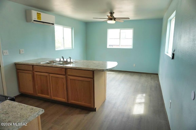 kitchen featuring a ceiling fan, a sink, a wall unit AC, and a wealth of natural light