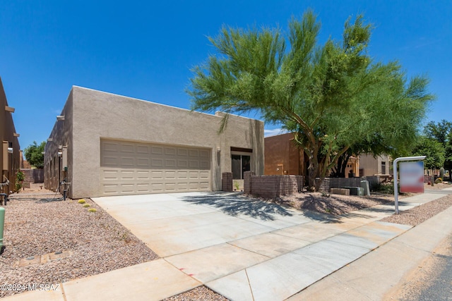 southwest-style home featuring a garage, concrete driveway, fence, and stucco siding