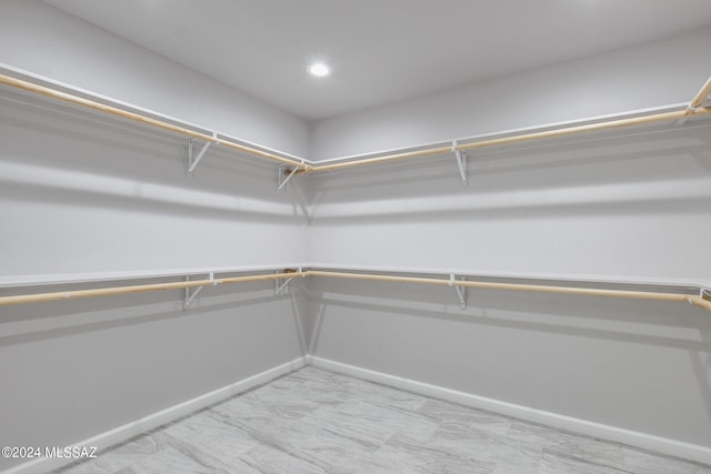 walk in closet featuring marble finish floor