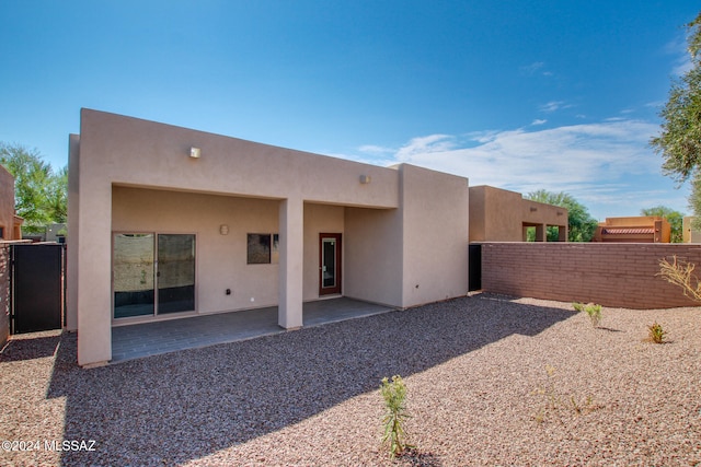 rear view of property featuring a patio area, fence, and stucco siding