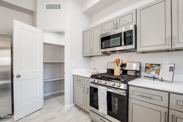 kitchen featuring visible vents, appliances with stainless steel finishes, light countertops, and gray cabinetry