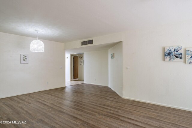 empty room featuring a notable chandelier and dark wood-type flooring