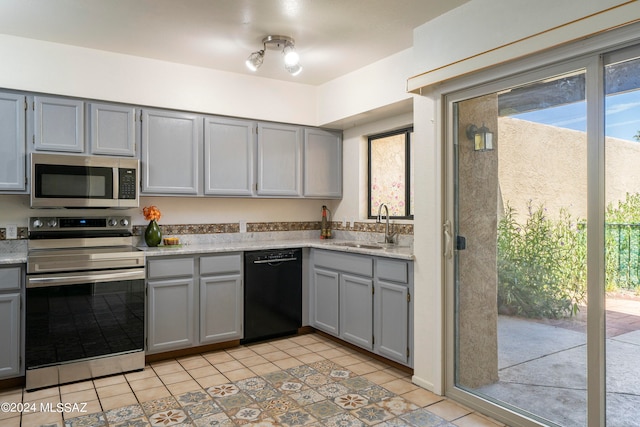 kitchen with gray cabinets, sink, light tile patterned flooring, and appliances with stainless steel finishes