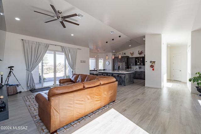 living area featuring light wood-style flooring, recessed lighting, visible vents, a ceiling fan, and vaulted ceiling