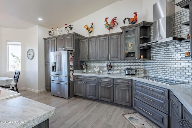 kitchen featuring wall chimney range hood, high quality fridge, and light countertops