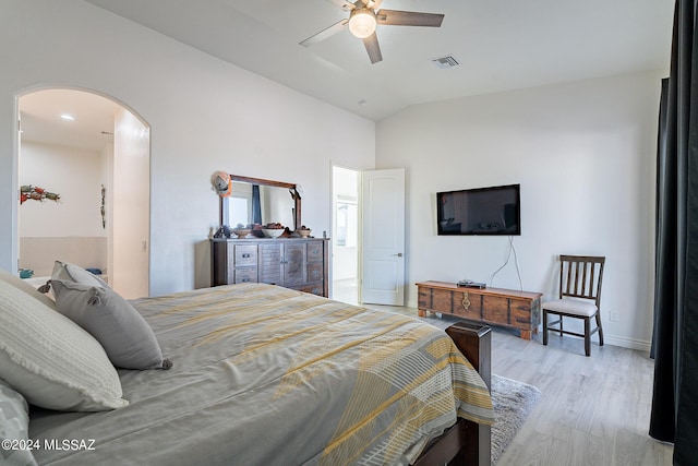 bedroom with baseboards, visible vents, arched walkways, lofted ceiling, and wood finished floors