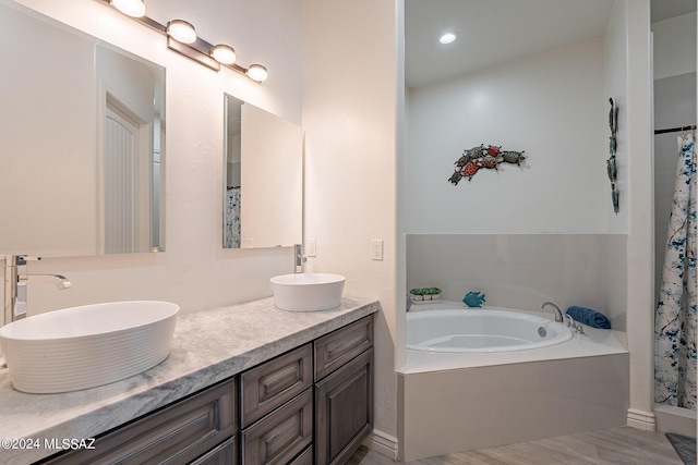 full bathroom featuring double vanity, a garden tub, curtained shower, and a sink