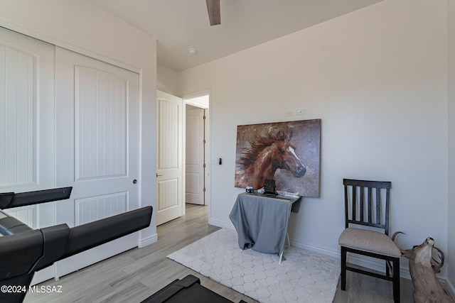 sitting room with a ceiling fan, baseboards, and wood finished floors