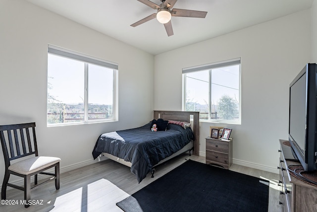 bedroom with multiple windows, wood finished floors, and baseboards