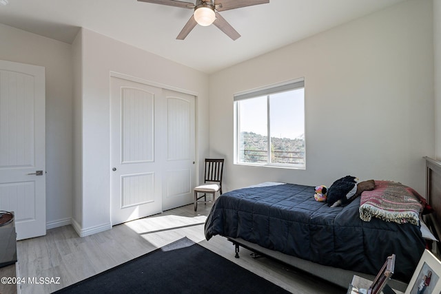 bedroom featuring light wood-style floors, a closet, ceiling fan, and baseboards